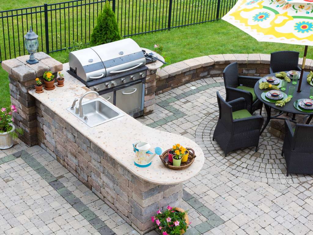 Outdoor kitchen and dining table on a paved patio. Boulder Falls provides custom outdoor kitchen installations in Vancouver WA and Camas WA.